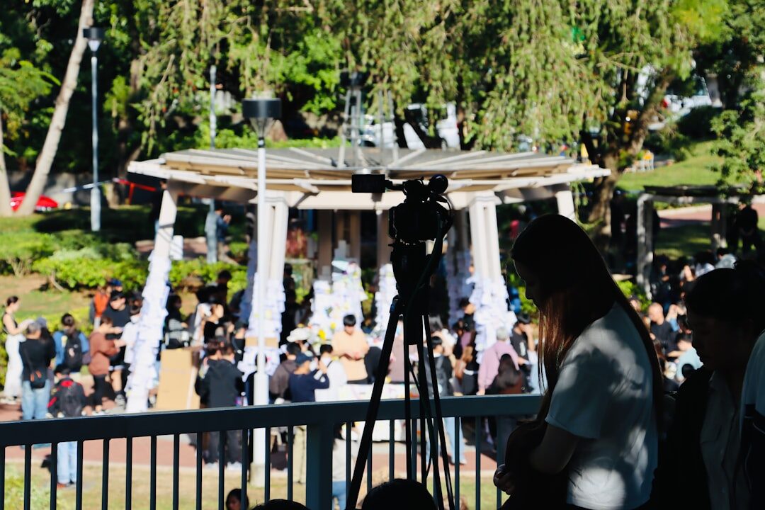 Video crew filming a live outdoor event with a crowd in the background